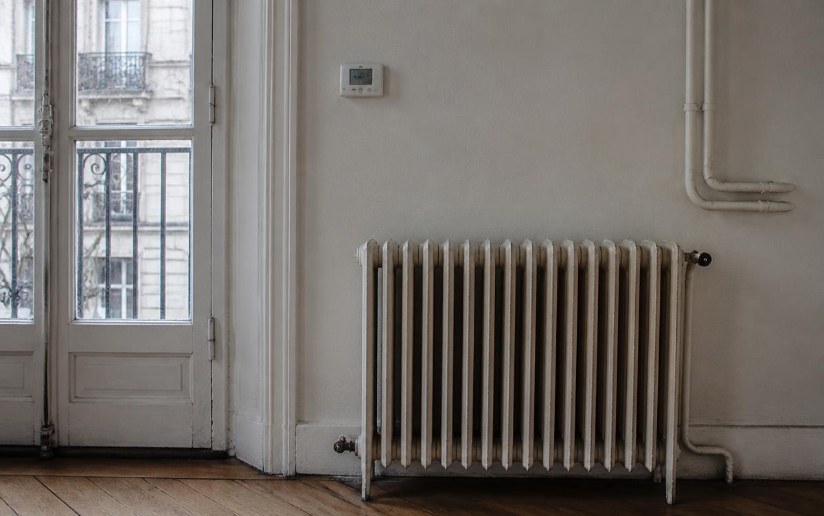 Radiateur ancien et thermostat sur le mur d'un appartement français
